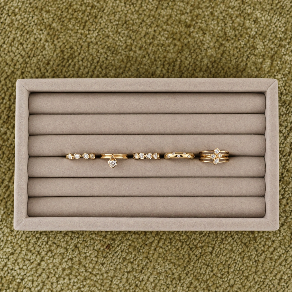 A curated collection of EMBLUME yellow gold and diamond rings, including heart, bezel and sculptural designs, displayed on a neutral jewellery tray.