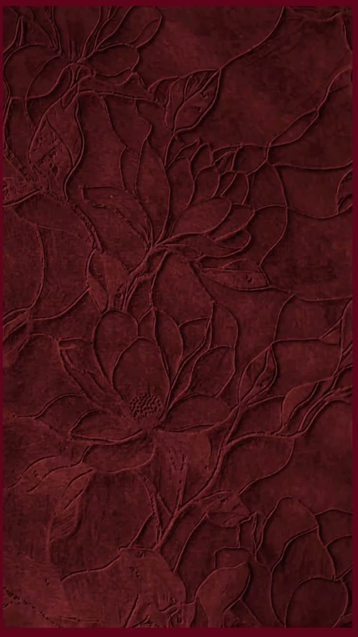 A close-up of a dark burgundy textured material with an embossed floral pattern.