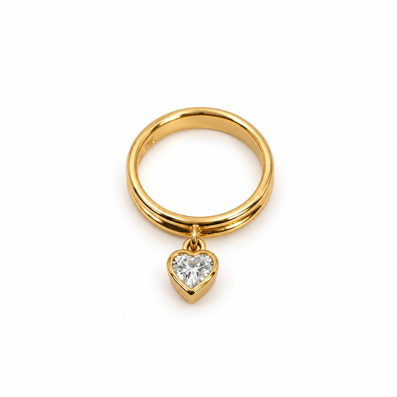 Yellow gold band with a suspended bezel-set heart-shaped diamond charm, photographed from above.
