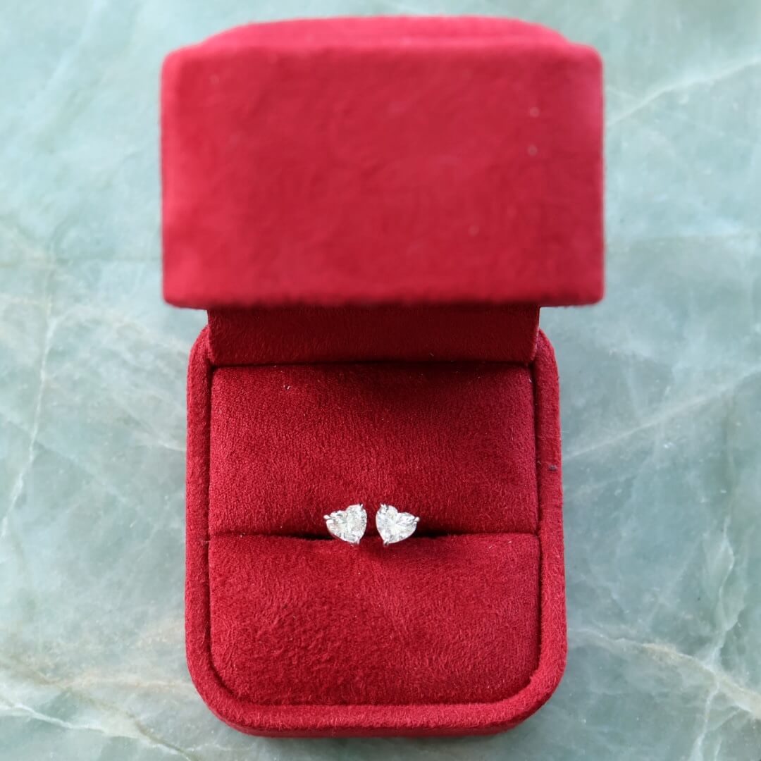 Pair of heart-shaped diamond stud earrings displayed in a jewellery box