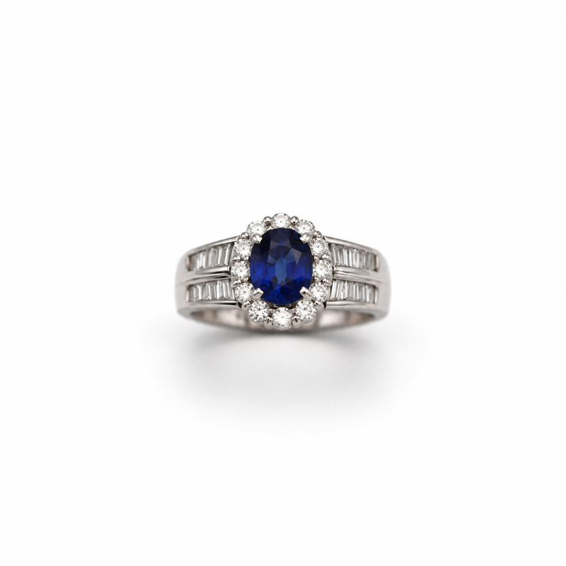 Oval sapphire and diamond halo ring in platinum with tapered baguette diamond shoulders by emblume